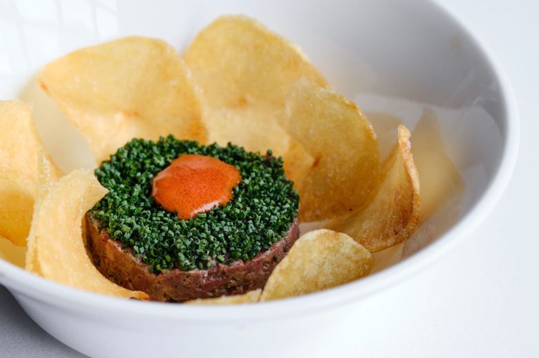Potato chips surround a disc of beef tartare topped with chives at Aria in Atlanta.