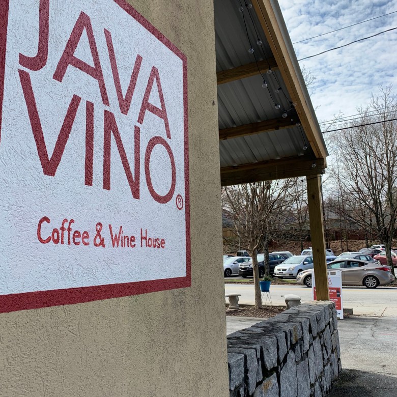 View of a building with a patio and "JAVA VINO" painted on the exterior wall. 