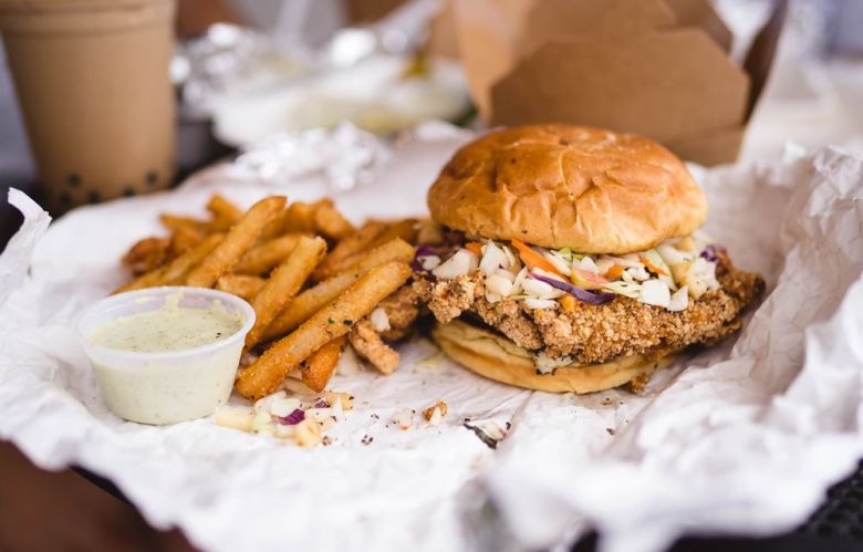 An oversized Taiwanese fried chicken breast topped with slaw in a bun served with fries from Java Saga on Buford Highway in Doraville, GA.